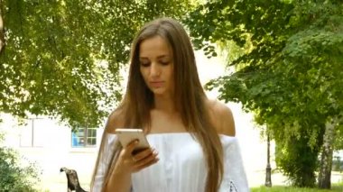   4 k. genç kadın güneşli Şehir Parkı içinde hareket eden smartphone kullanın. 