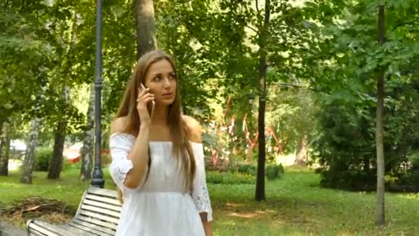 Jovem Mulher Cabelo Longo Falar Smartphone Móvel Ensolarado Parque Cidade — Vídeo de Stock