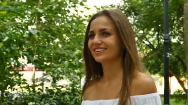 Çekici mutlu genç uzun - saç kadında şehir yaz park gülümsüyor. Ağır çekim, sürekli çekim