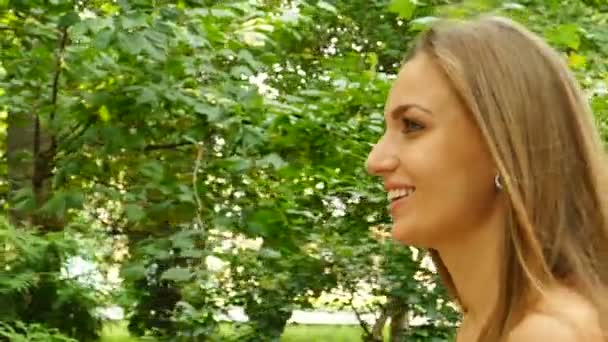 ロング 公園夏の髪の女性が歩くし 笑顔は魅力的です 動きが遅い 安定したショット 側面図 — ストック動画
