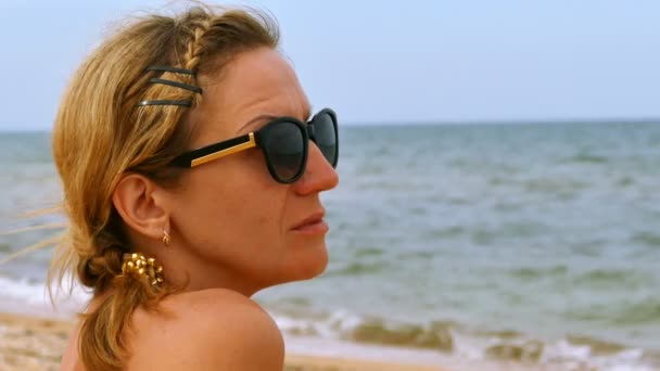 妇女坐在海边沙滩上 看海面 脸部特写 — 图库视频影像