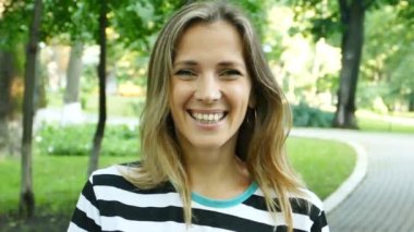 Ağır çekim. Şehir Parkı, güzel kadın portresi parlak fotoğraf makinesindeki gülümsüyor. sürekli çekim