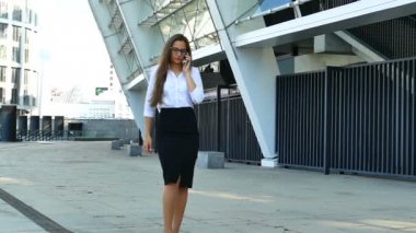 Ağır çekim. Bölge ofisinde yürüme çekici iş kadını gülümseyen ve smartphone ile konuşmak