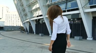 Ağır çekim. Oldukça uzun saç iş kadını office bölgede yürüyüş geri çevirir ve gülümseme