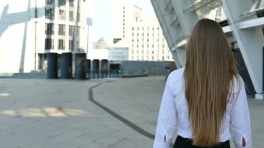 Ağır çekim. Genç uzun saç iş kadını office bölgede yürüyüş geri çevirir ve gülümseme