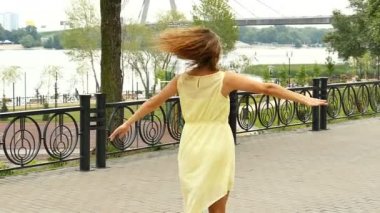 Ağır çekimde sarı elbiseli şehir sokak dansları mutlu uzun saçlı kız. Sürekli çekim