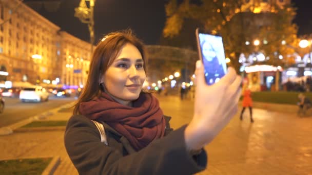 和女性半アジア人の顔を夜の街での携帯電話のスマート フォン Selfie を行います 背景をぼかした写真 — ストック動画
