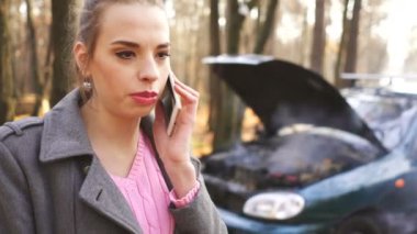 4 k. araba sorun duman ve çekici genç kadın çağrı smartphone için yardım tarafından.