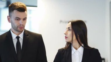 4k. Modern iş adamı ve güzel iş kadını ofiste bir şey hakkında konuşalım. Sürekli çekim