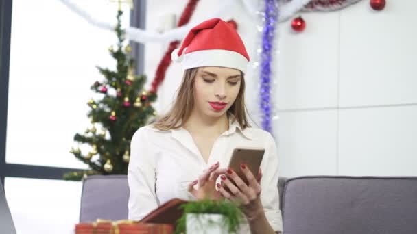 Junge Geschäftsfrau Mit Rotem Weihnachtsmann Hut Tippt Smartphone Auf Den — Stockvideo