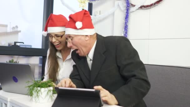 商人和女商人戴着圣诞老人的红色帽子 笑着看着显示器 — 图库视频影像