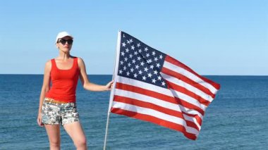 Deniz kenarında Amerikan bayrağı ile uyumlu vatansever güzel kadın stand. 