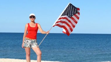Deniz kenarında Amerikan bayrağı ile ciddi kadın stand. Ağır çekim