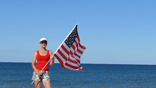 明亮的妇女站立与美国旗子在海附近 慢动作 — 图库视频影像