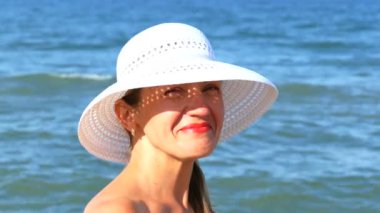    Gözlük, okyanus dalgalarının ayakta beyaz şapkalı 4 k. güzel kadın koymak