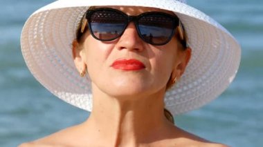    beyaz şapka ve gözlük, okyanus dalgalarının duran 4 k. güzel kadın. Portre, yüz yakın çekim