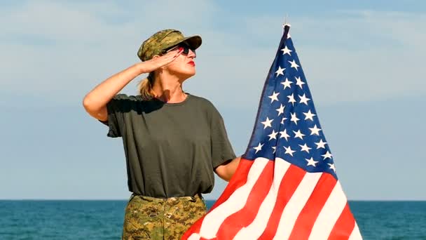 Γυναίκα Στρατιώτης Χαιρετισμό Στέκεται Αμερικανική Σημαία Κοντά Στη Θάλασσα Αργή — Αρχείο Βίντεο