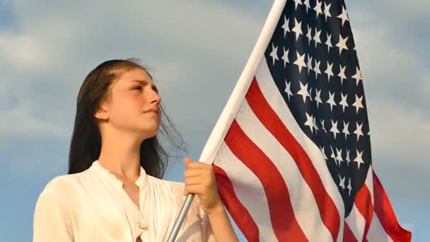 严肃的女孩站在美国国旗对蓝天 慢动作 — 图库视频影像