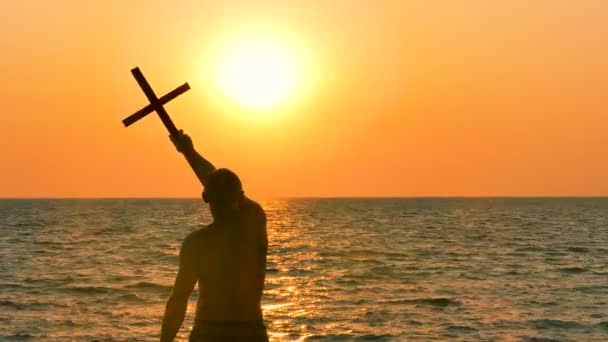祈祷者挥手致意的基督徒横渡反对海洋橙色日落或日出 后视图 — 图库视频影像