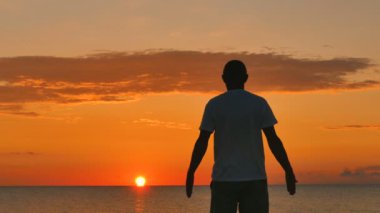 4. erkek deniz günbatımı veya gündoğumu karşı derin derin düşünür. Ellerini yukarı kaldır