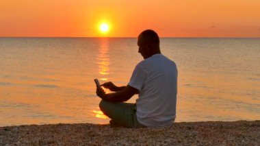 4. adam iş ile smartphone deniz günbatımı ve gündoğumu karşı .