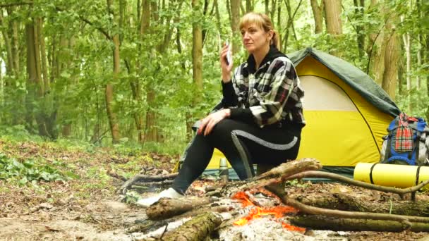 妇女游客附近帐篷和篝火谈话的移动 户外生活 — 图库视频影像