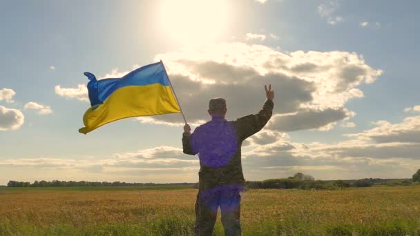 旗を持つウクライナの兵士は 太陽と夕方の空に対してため息を示す 屋外スローモーションシーン — ストック動画