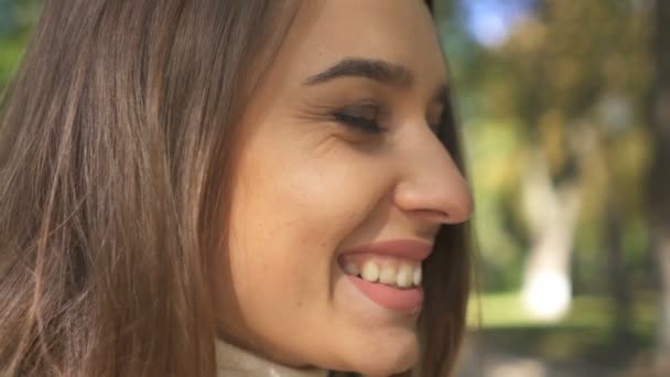 かなり若い笑顔の女性 春の市の公園で女の子の顔 クローズ アップ シーン — ストック動画