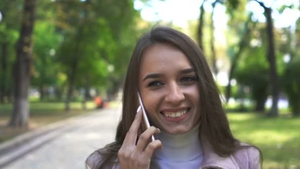 매력적인 여자는 화창한 공원에서 스마트 폰으로 이야기 꾸준한 — 비디오