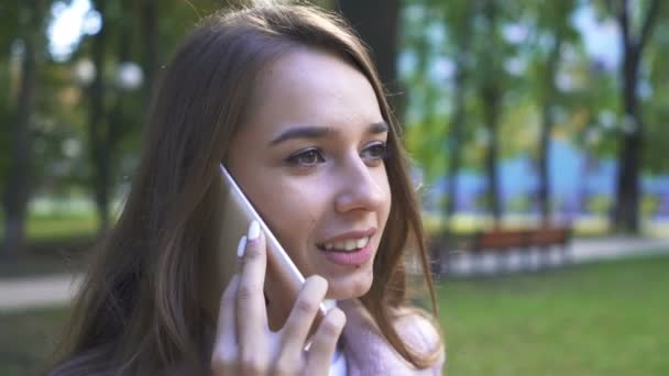 サニー シティ パークで 若い笑顔の女性がスマートフォンで話します 安定したショット — ストック動画