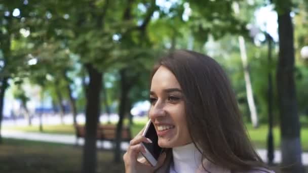 Молодая Улыбающаяся Женщина Разговаривает Смартфону Городском Парке — стоковое видео