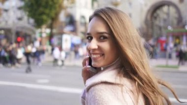   4k. genç mutlu kadın yürümek ve şehir sokakta Smartphone tarafından konuşmak, kameraya bak. Sabit atış