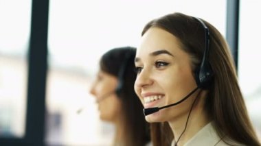 4k. Office çağrı merkezi çalışması. İki genç gülümseyen kadın operatörler müşteri cevap 
