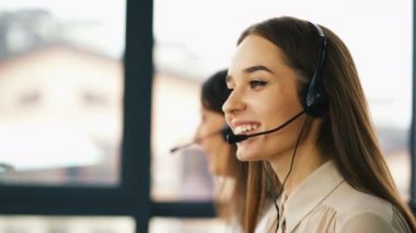 4k. Iki genç gülümseyen kadın operatörleri müşteri cevap. Office çağrı merkezi çalışması.  