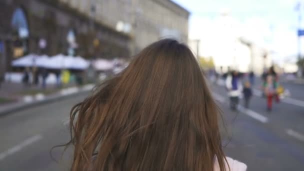 若い幸せな女性が歩くと朝の街の通りにターン 安定したショット スローモーション — ストック動画