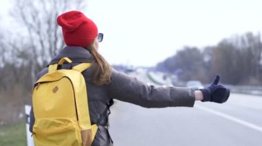                          Genç kadın otostop, parmağınızı yukarı çekin. Arka görünüm, yay 