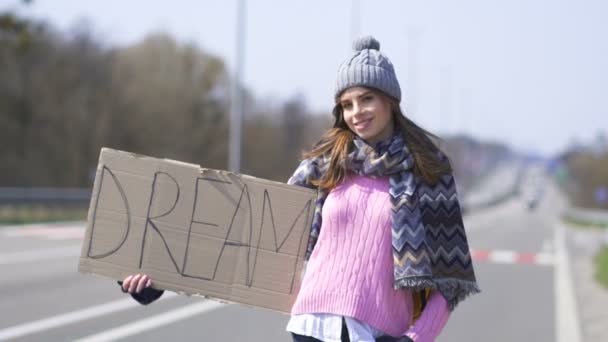 若いかわいい笑顔の女性は ポスターの夢で車を止めるヒッチハイク — ストック動画