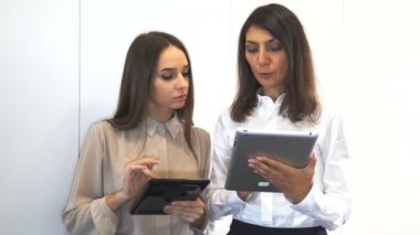 4. ofis çalışma süresi. İki seksi iş kadınları tablet bilgileri hakkında tartışmak. 
