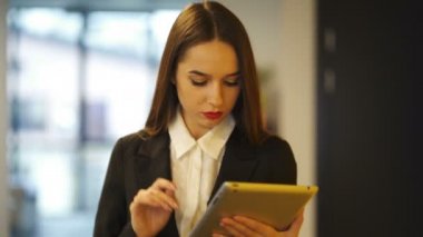 4. Çekici ciddi genç iş kadını ofiste tablet ile yürümek . Sabit atış