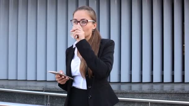 年轻而严肃的女商人在城市街道上输入智能手机 喝咖啡 — 图库视频影像