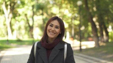   4 k. Şehir parkında oldukça parlak gülümseyen Asyalı kadın . Kameraya bakmak