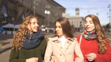  4k. Üç genç güzel kadın kız gülerek şehir caddesinde yürümek. Sabit atış