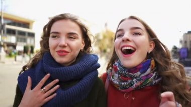   4k. Genç kadın kardeş ikizler modelleri gülümseyerek şehir caddesinde yürümek. Sabit portre çekimi