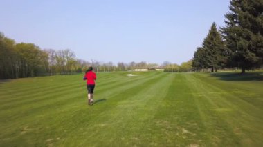  4 k. Hava. Kadın koşucu boş yolda koşuyor. Üstte görüntü