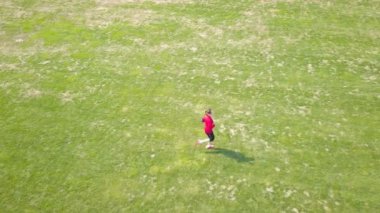 4 k. Hava. Kadın koşucu yeşil sahada koşuyor. Sportif kadın üzerinde fly, üst görünümü