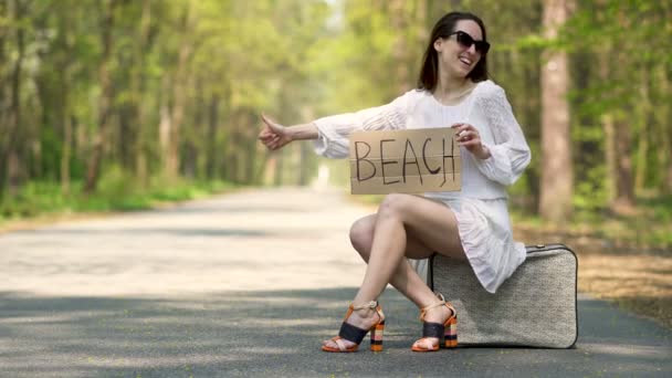 Mujer Sonriente Autostop Sentarse Maleta Retro Con Cartel Playa — Vídeos de Stock