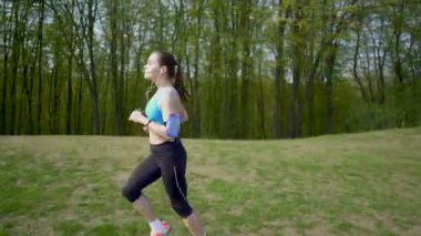 4 k. Yetişkin güzel kadın koşucu yeşil alanda koşmak, kulaklık müzik dinlemek. Sabit atış