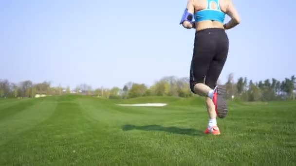 Szczęśliwa Kobieta Biegacz Biegać Zielonym Polu Słuchać Muzyki Słuchawkach Stabilny — Wideo stockowe