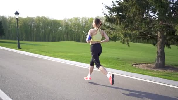 女性ランナーは空の道を走る 朝だスローモーション バックビュー 安定したショット — ストック動画