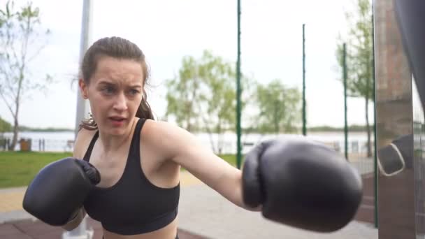 慢动作 年轻女子拳击手在街头城市训练场上用拳袋训练 稳定的射门 面朝近 自卫小组 — 图库视频影像